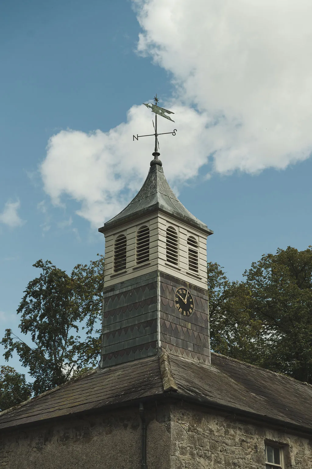 The clock tower and weathervane against a summer sky