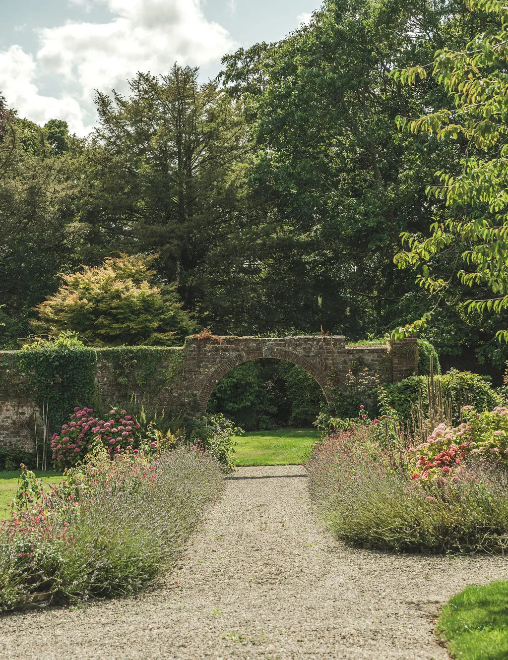 A stone arch in the walled garden framed by late-summer flowers