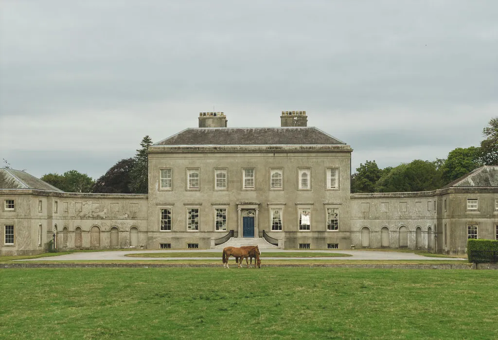 The Palladian facade of Ardbraccan Manor House, horses grazing before it