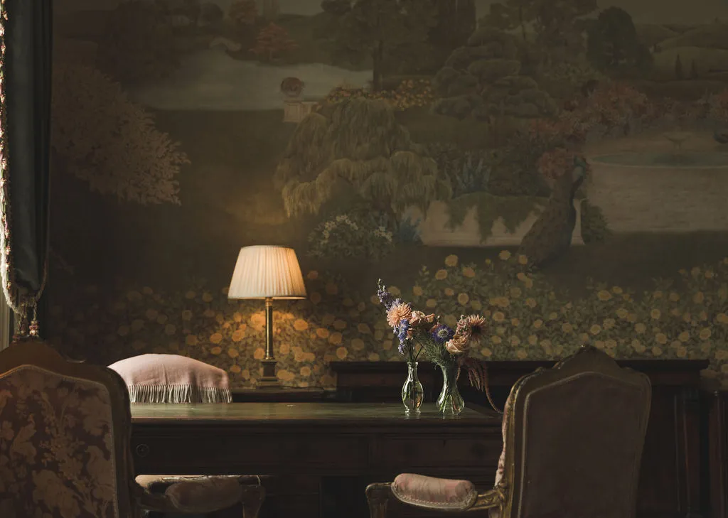 Lamplight on an antique desk before a tapestry
