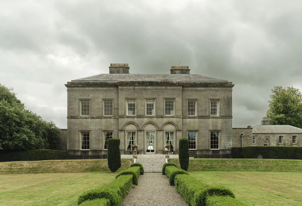 Ardbraccan Manor House beneath a brooding sky, box hedges lining the approach