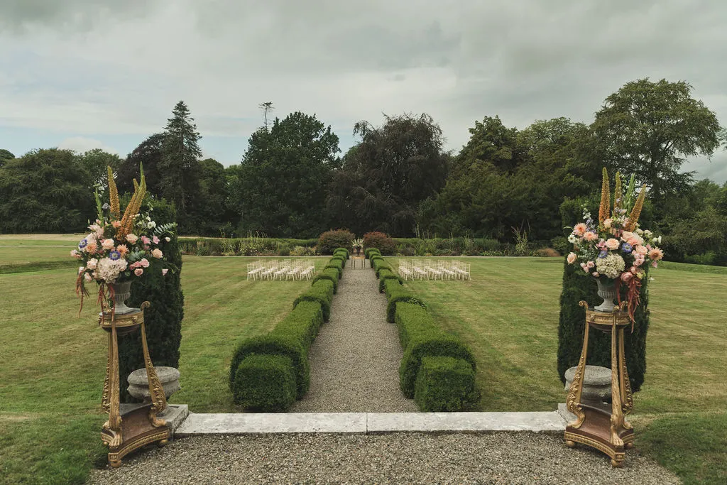 The walled garden ceremony aisle, flower urns either side of the entrance