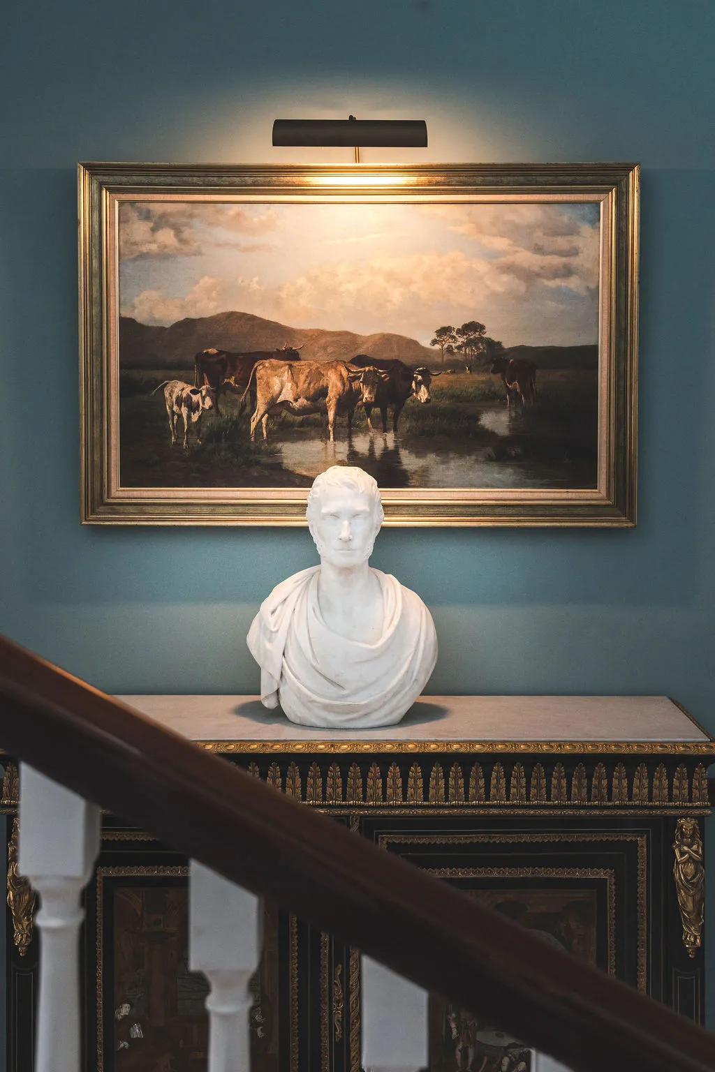 A marble bust beneath a painting in the blue staircase hall