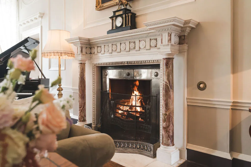 An open fire burning beneath a carved marble chimneypiece