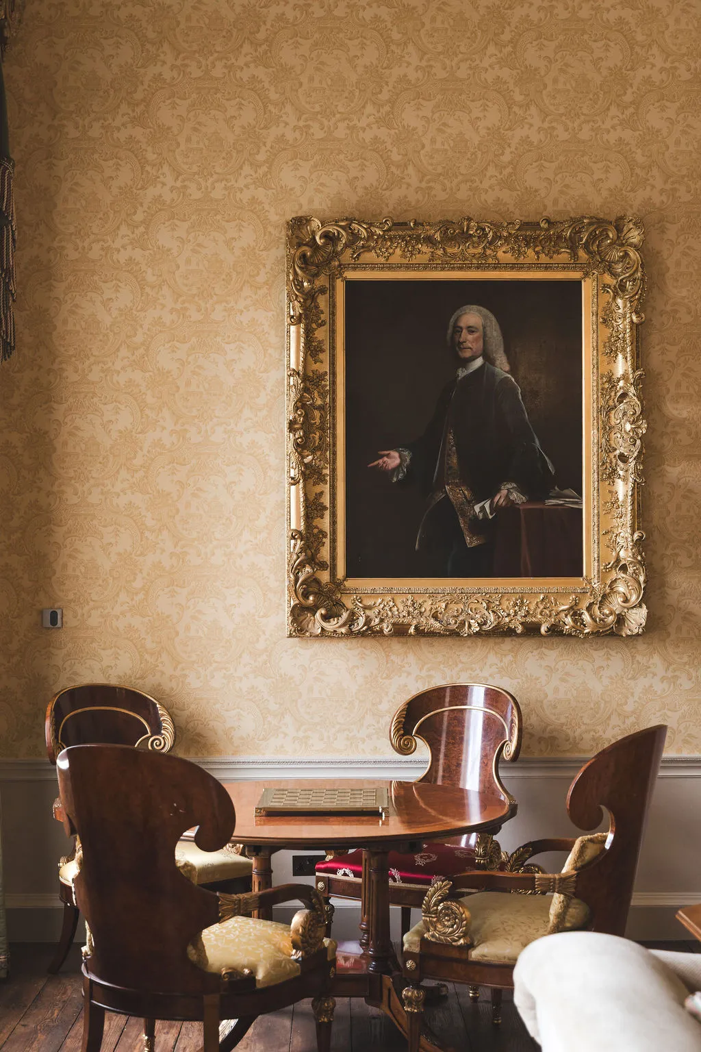 A gilt-framed portrait above an antique table in a reception room