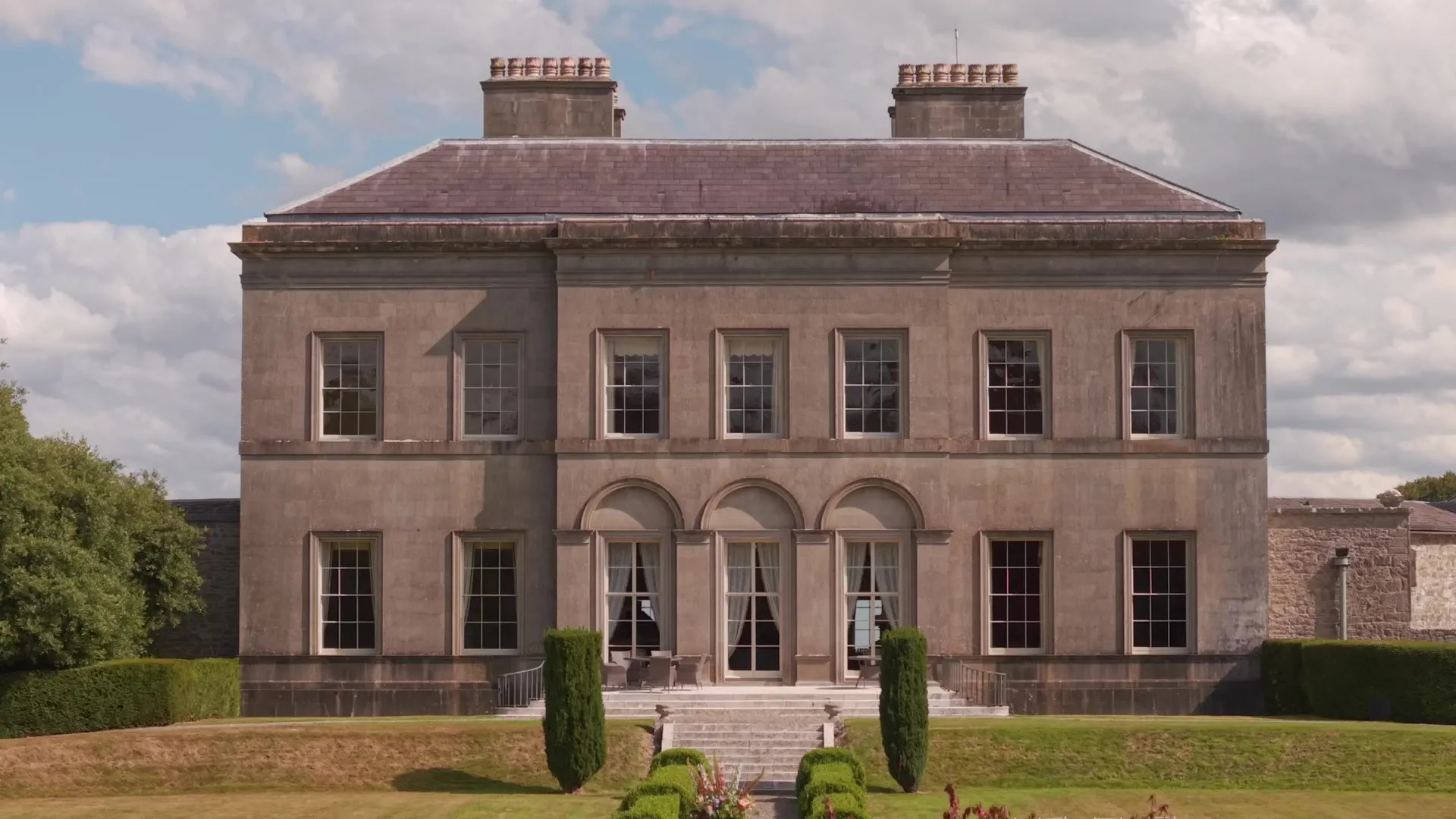 The sunlit facade of Ardbraccan Manor House above its formal garden